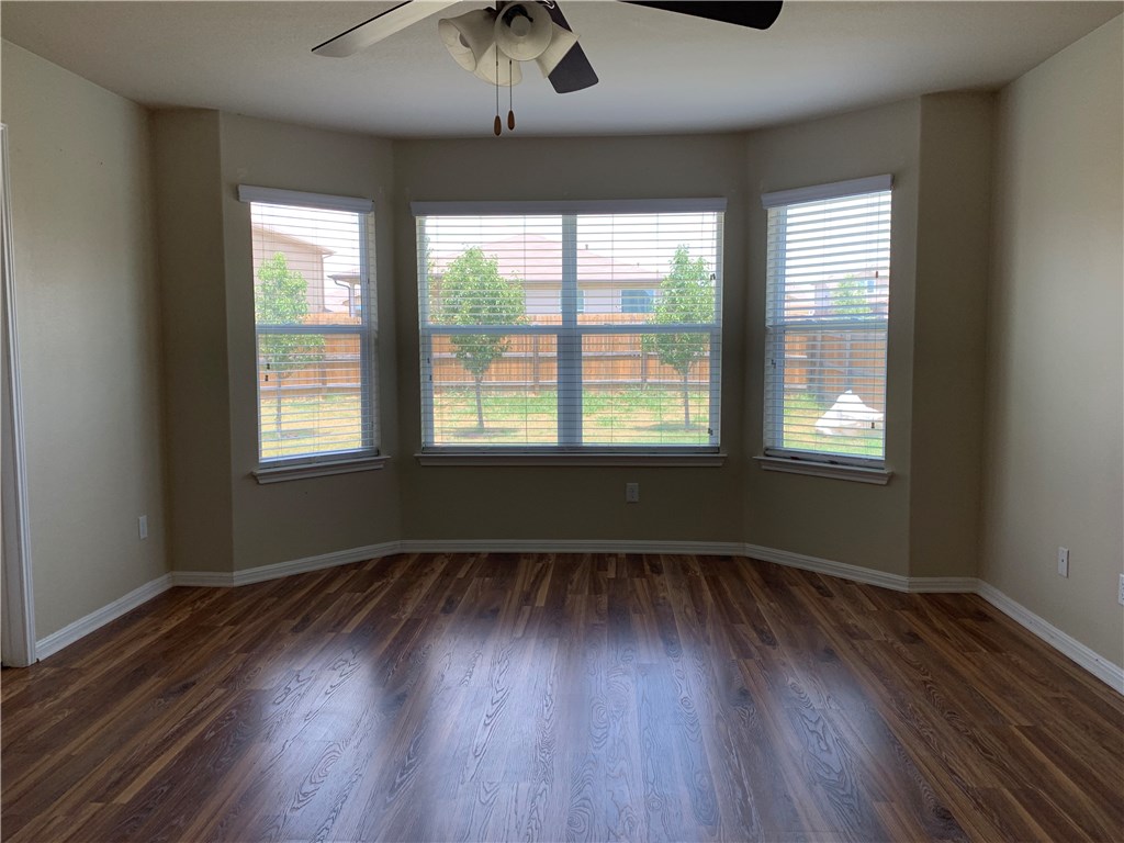 151 Chickadee Cove Kyle, TX 78640 - Photo 7 of 29 an empty room with wooden floor and windows