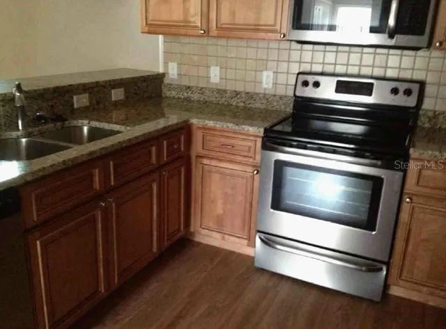 a kitchen with granite countertop wood cabinets and stainless steel appliances