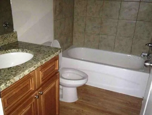 a bathroom with a granite countertop bathtub sink vanity mirror and toilet