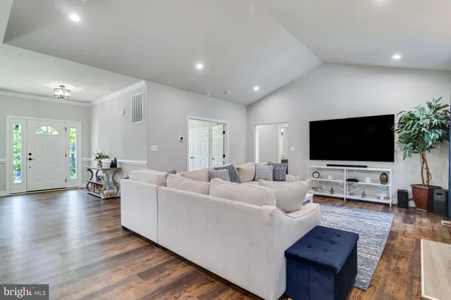 a kitchen with stainless steel appliances granite countertop a refrigerator a stove top oven a sink dishwasher and couches with wooden floor