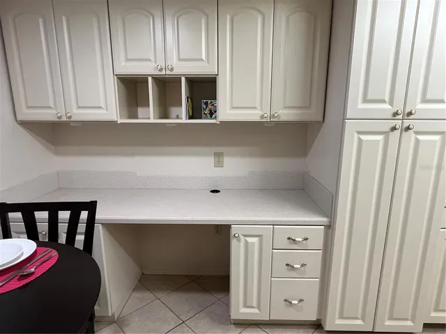 a kitchen with white cabinets and window