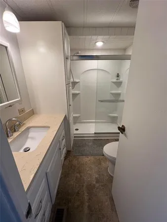 a bathroom with a granite countertop sink a mirror and shower