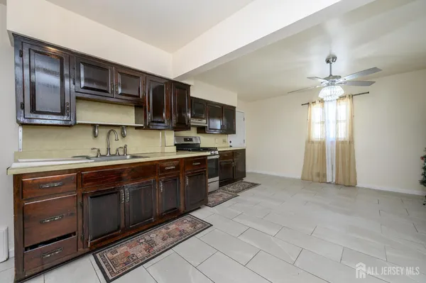 an empty room with chandelier fan and windows