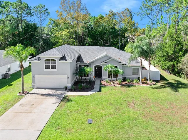 a front view of house with yard and trees in the background