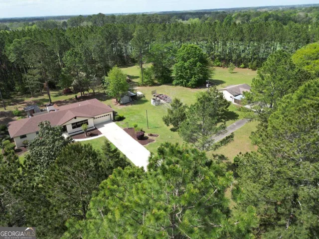 an aerial view of residential house with outdoor space and trees all around