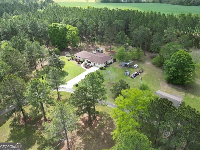 an aerial view of residential house with outdoor space and trees all around