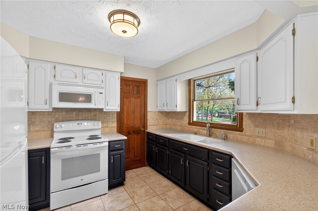 5346 Burlawn Street Northwest Canton, OH 44708 - Photo 11 of 40 Kitchen featuring tile flooring, a dual-basin sink, a tile backsplash, and a white oven with an overhead microwave