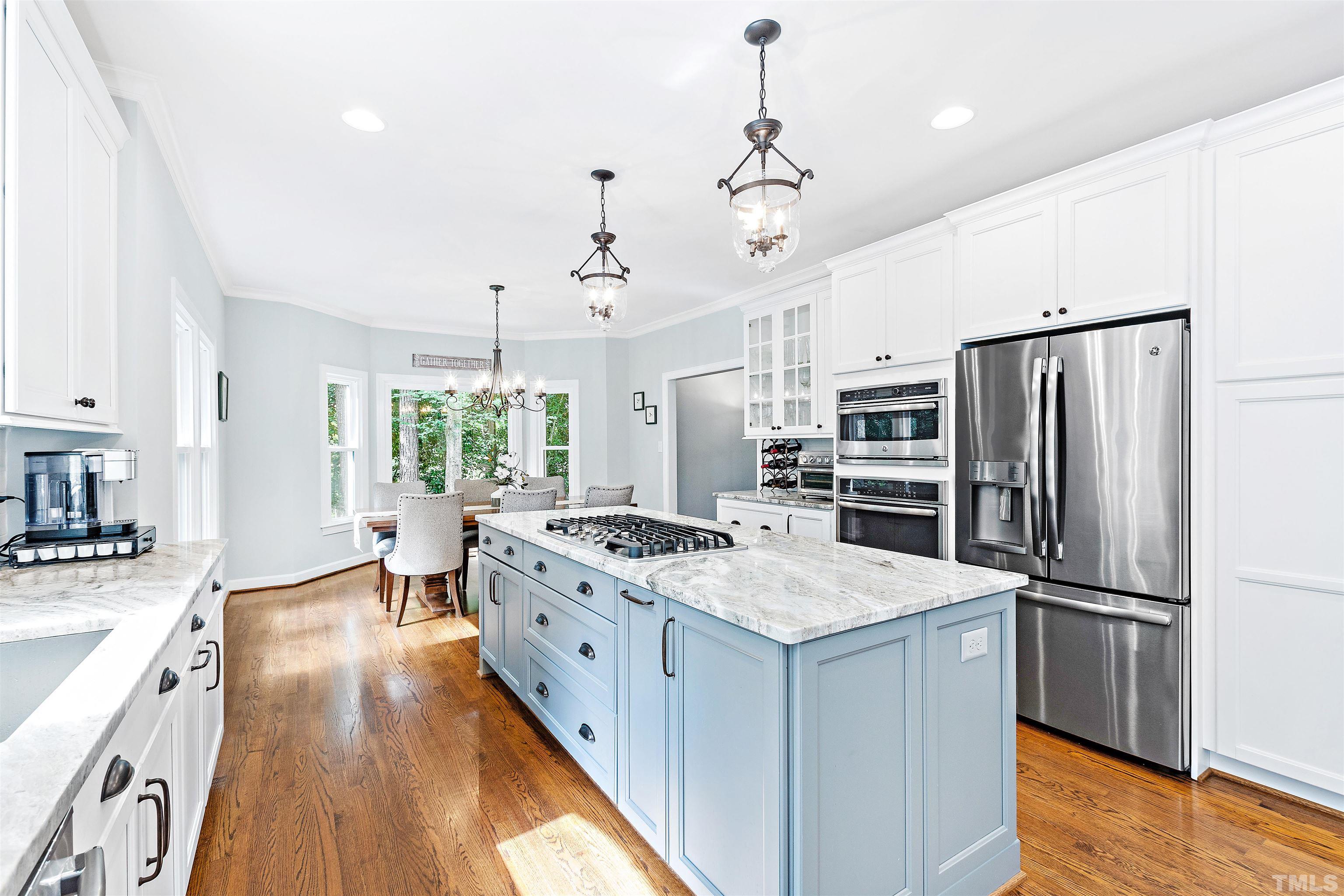 4708 Fallswood Place Raleigh, NC 27613 - Photo 7 of 45 a kitchen with a center island wooden floor and stainless steel appliances