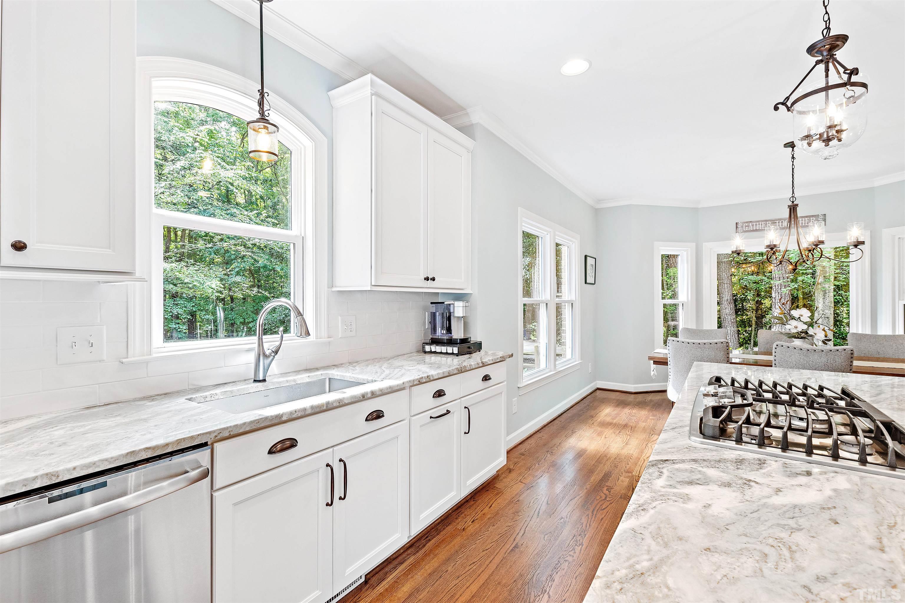 4708 Fallswood Place Raleigh, NC 27613 - Photo 9 of 45 a large kitchen with kitchen island white cabinets and wooden floor