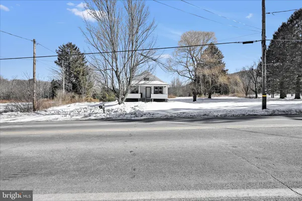 a front view of a house with a yard covered with snow and trees