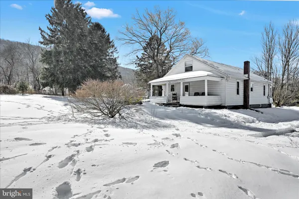 a white house with a large tree with wooden fence