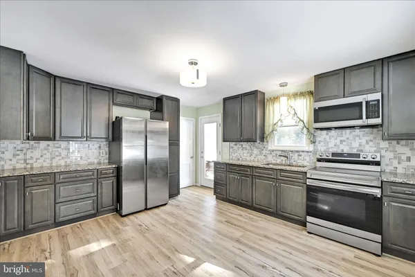 a kitchen with stainless steel appliances granite countertop a refrigerator and a stove top oven