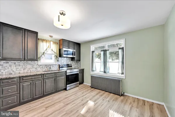 a kitchen with stainless steel appliances granite countertop a stove a sink dishwasher and a microwave oven with white cabinets