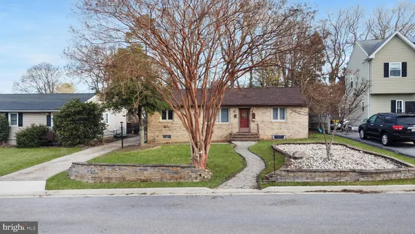 a front view of a house with a garden and trees