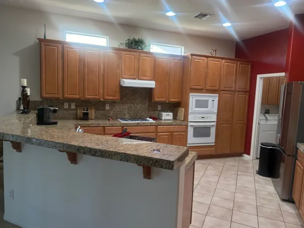 a kitchen with stainless steel appliances granite countertop a refrigerator a stove a sink and a microwave