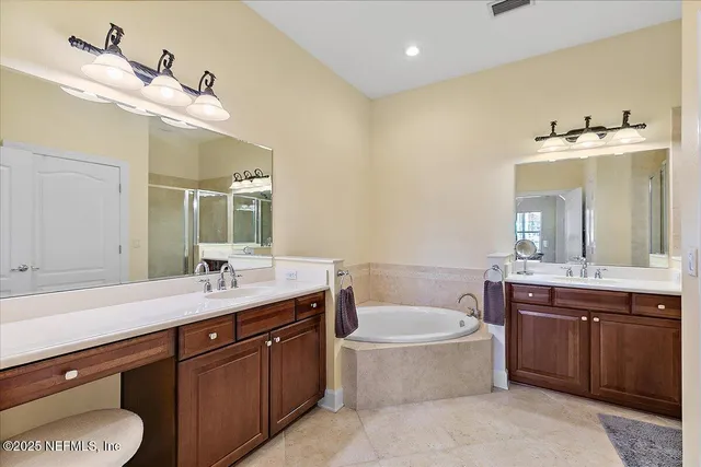 a spacious bathroom with a tub double sink and mirror