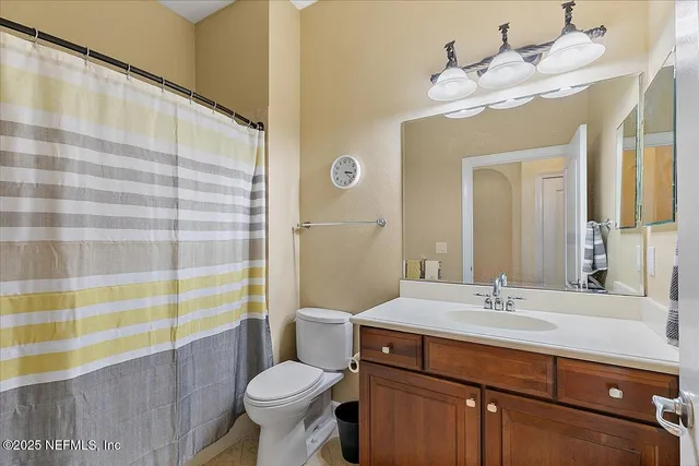 a bathroom with a sink a toilet a mirror and shower curtain