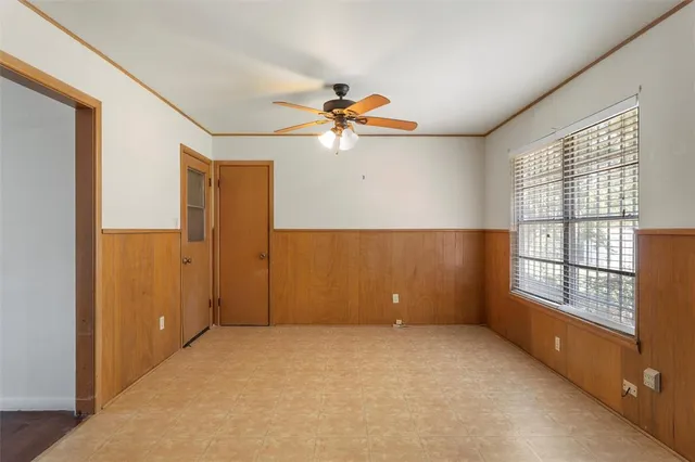 an empty room with chandelier fan and windows