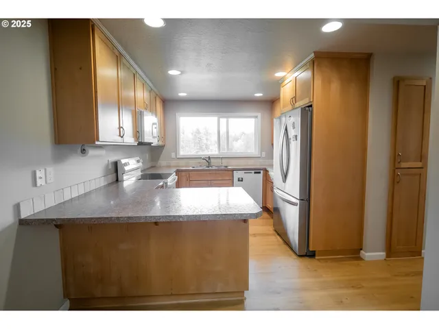 a kitchen with stainless steel appliances granite countertop a sink a refrigerator and a granite counter tops