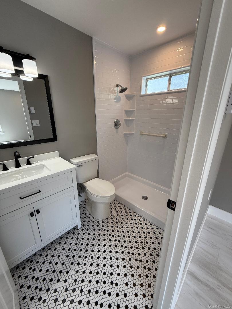 379 Larchmont Court Ridge, NY 11961 - Photo 12 of 17 a bathroom with a sink toilet a mirror and shower