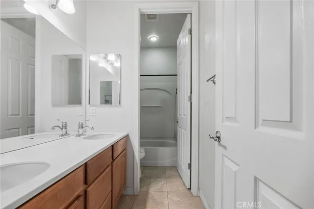 a bathroom with a double vanity sink a toilet and shower
