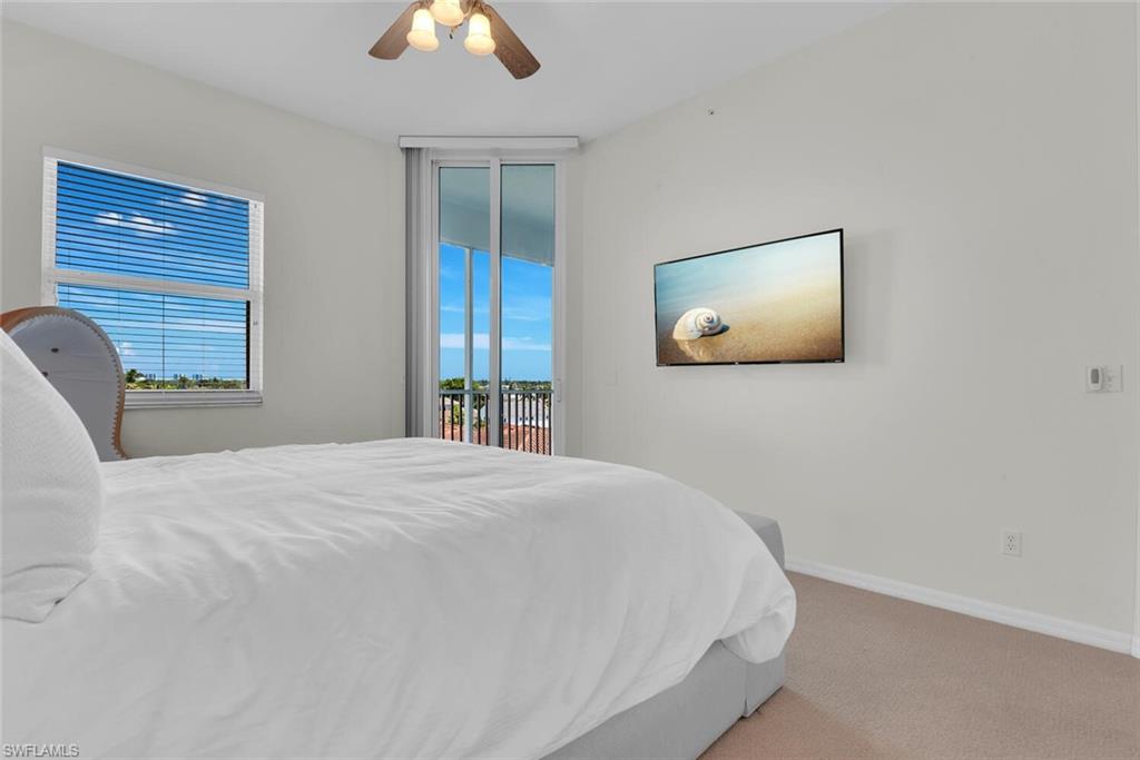 450 Launch Circle, Unit 602 Naples, FL 34108 - Photo 12 of 27 a bedroom with a bed and a chandelier