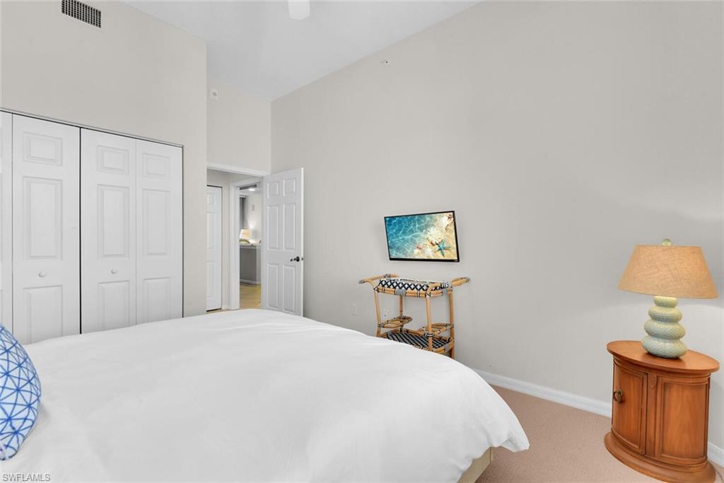 450 Launch Circle, Unit 602 Naples, FL 34108 - Photo 15 of 27 a bedroom with a bed and a lamp on table