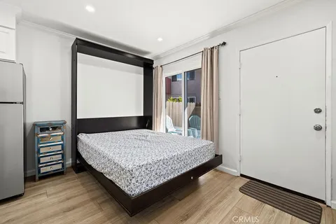 a bedroom with a bed and a dresser with wooden floor