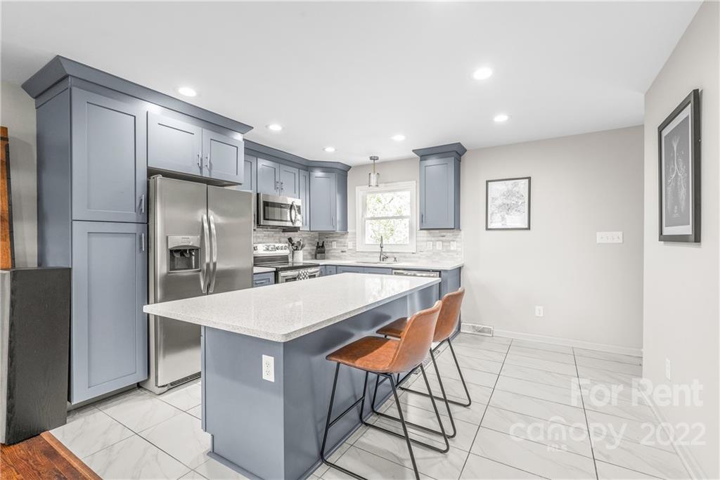 3932 Slagle Drive Charlotte, NC 28215 - Photo 10 of 26 a kitchen with stainless steel appliances refrigerator stove microwave and cabinets