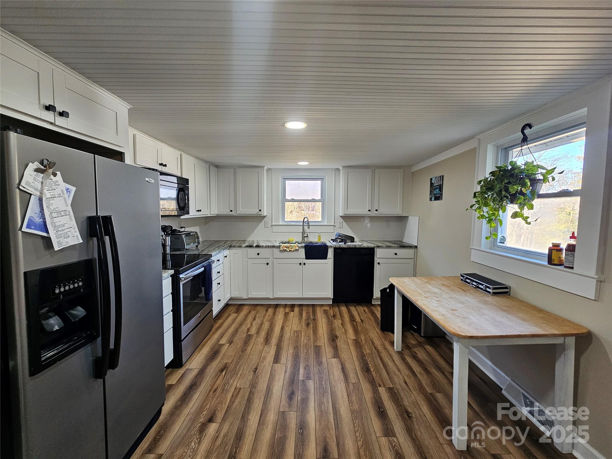 208 West Main Street Lawndale, NC 28090 - Photo 5 of 15 a kitchen with stainless steel appliances a refrigerator a sink dishwasher a stove top oven a dining table and chairs with wooden floor
