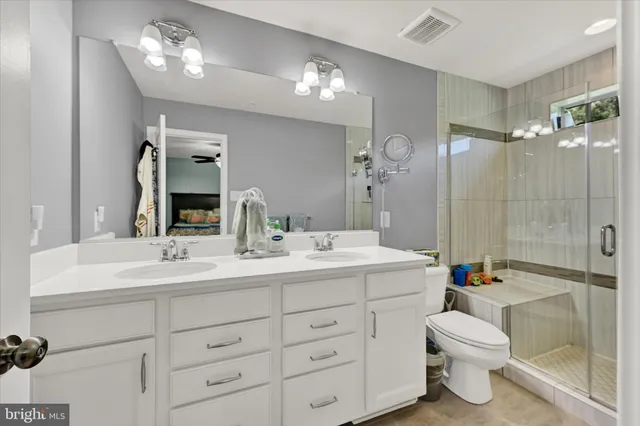 a bathroom with a double vanity sink toilet mirror and shower