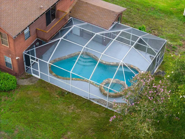 a backyard of a house with plants and a large tree