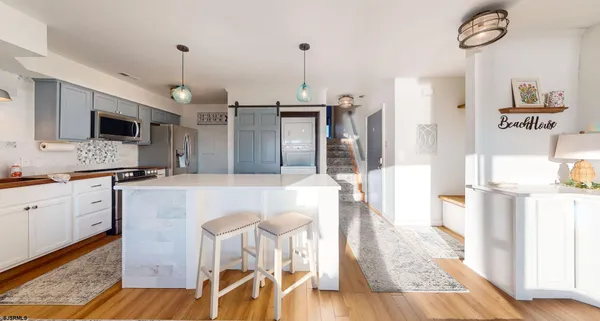 a open kitchen with stainless steel appliances kitchen island granite countertop a stove a sink dishwasher and a refrigerator with wooden floor