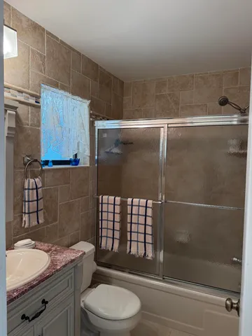 a bathroom with a granite countertop bathtub shower sink vanity and toilet