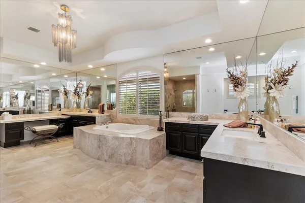 a bathroom with a tub a double vanity sink and glass door