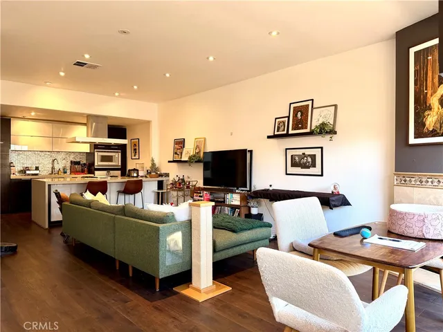 a living room with furniture a flat screen tv and kitchen view