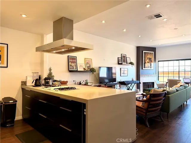 a kitchen with a stove a sink dishwasher and a dining table with wooden floor