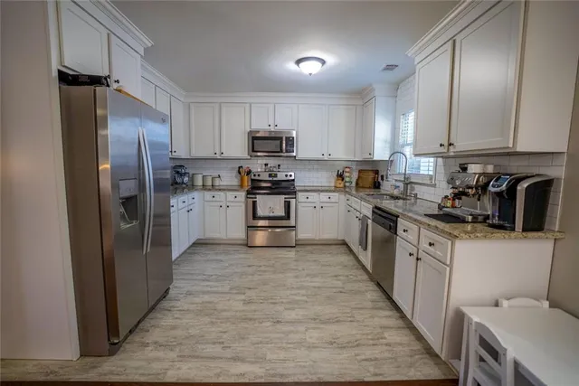 a kitchen with stainless steel appliances granite countertop a refrigerator a stove top oven a sink and dishwasher