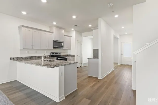 a kitchen with stainless steel appliances granite countertop a stove top oven a sink and a refrigerator