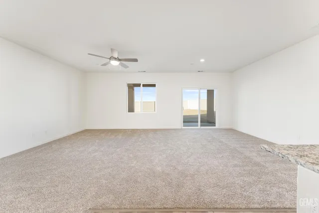 an empty room with windows and ceiling fan