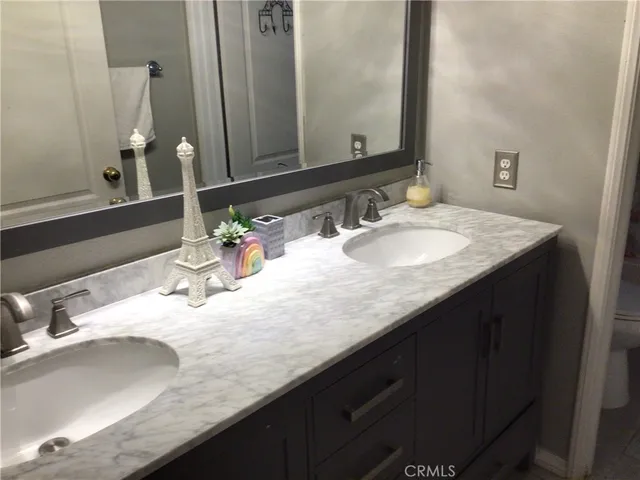 a bathroom with a granite countertop double vanity and a mirror