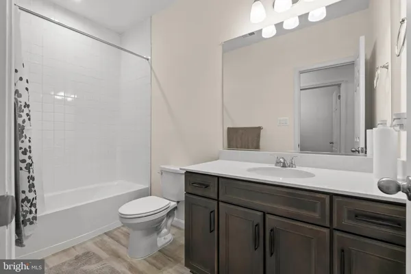 a bathroom with a granite countertop sink toilet a large mirror a shower and a bathtub