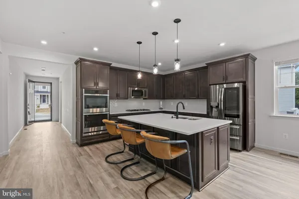 a large kitchen with a table chairs refrigerator and wooden floor