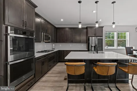 a kitchen with stainless steel appliances granite countertop a sink a stove a refrigerator and island