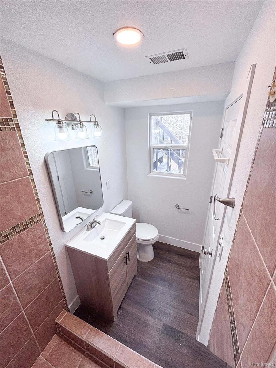 4295 Genoa Street Denver, CO 80249 - Photo 18 of 28 a bathroom with a toilet a sink a mirror and a window