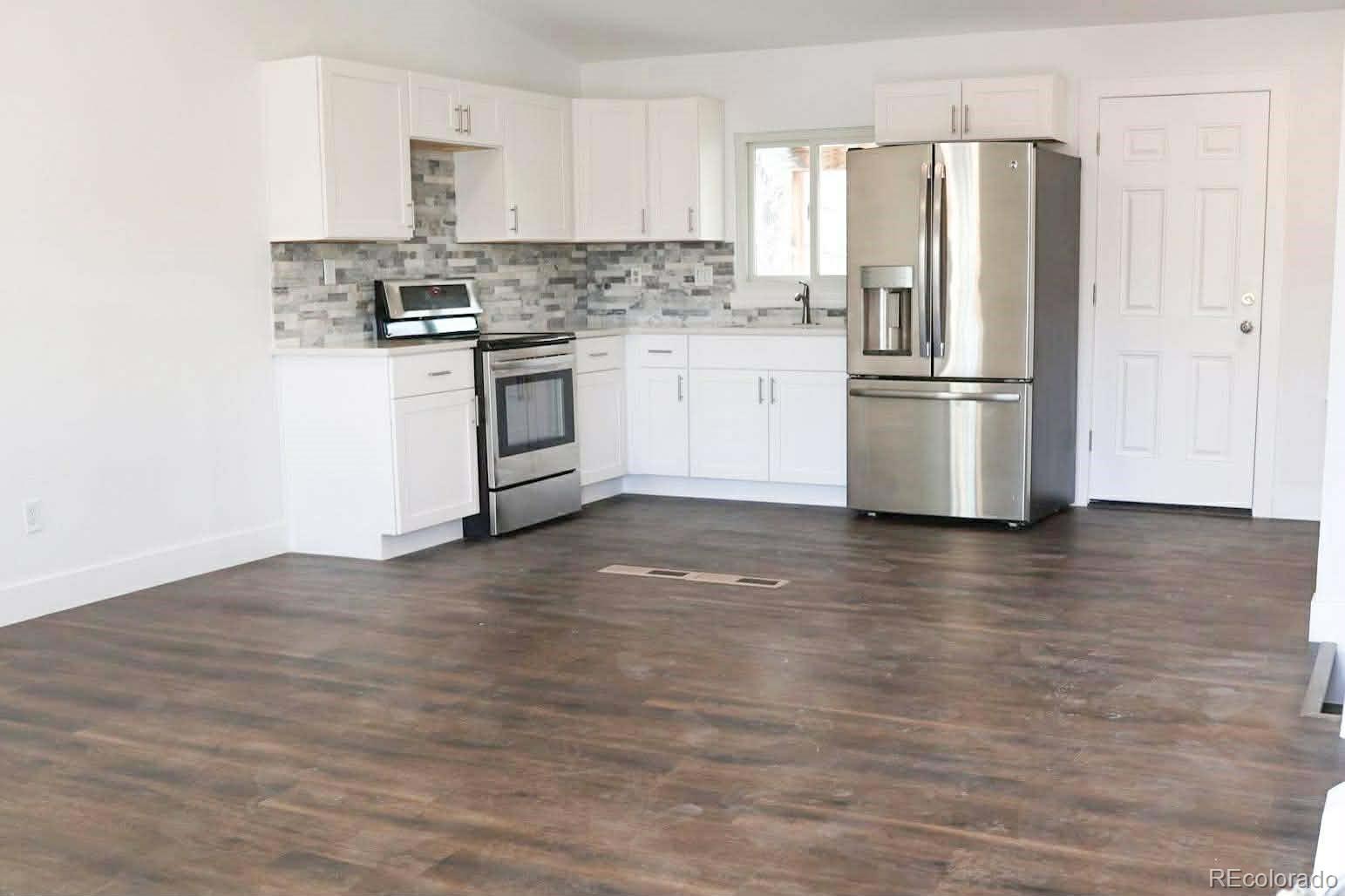 4295 Genoa Street Denver, CO 80249 - Photo 4 of 28 a kitchen with stainless steel appliances wooden floor and a refrigerator
