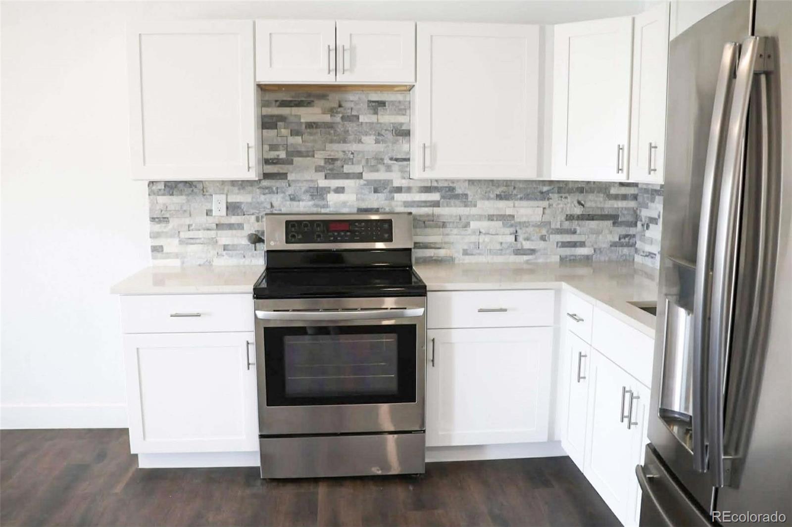 4295 Genoa Street Denver, CO 80249 - Photo 5 of 28 a kitchen with white cabinets and white appliances
