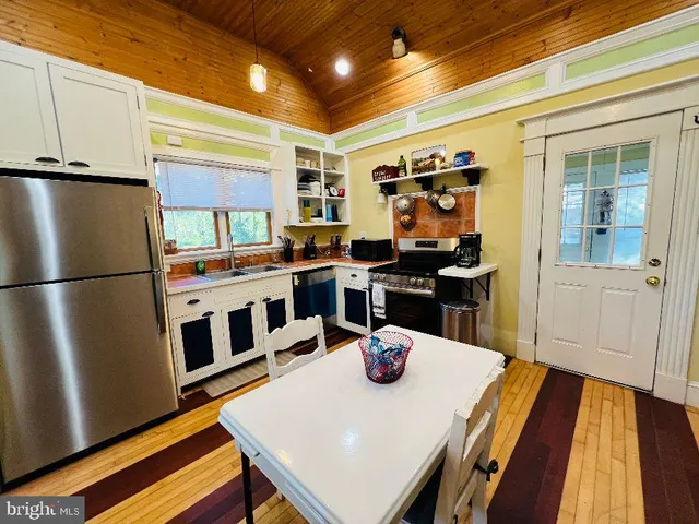 a kitchen with stainless steel appliances granite countertop a refrigerator a stove and a dining table with wooden floor