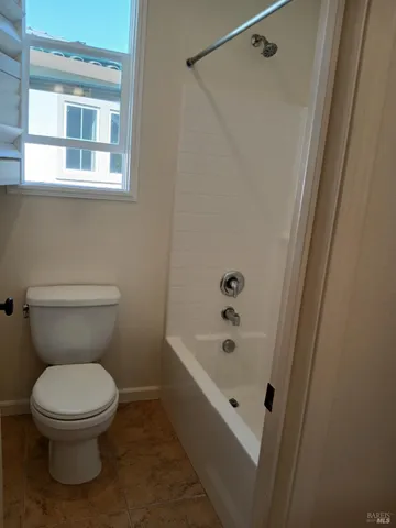 a white toilet sitting next to a bath tub