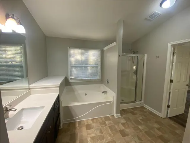 a bathroom with a tub sink shower and mirror